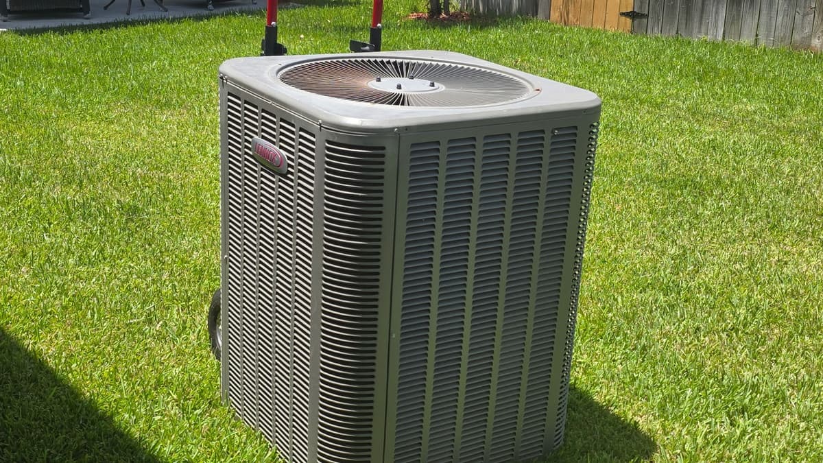 Outdoor condensing unit standing on a clear, well-kept lawn after a seasonal tune-up