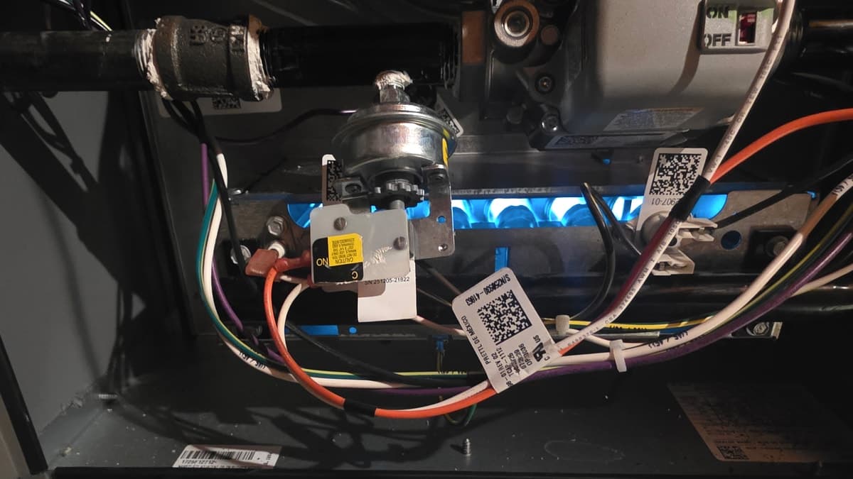 Gas furnace burners alight with the burner compartment open during a heating service call